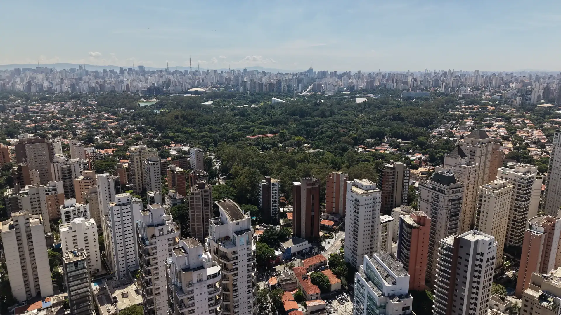 Torres de Moema e da Vila Nova Conceição, a mata do Parque Ibirapuera e a cidade ao fundo. Foto aérea.