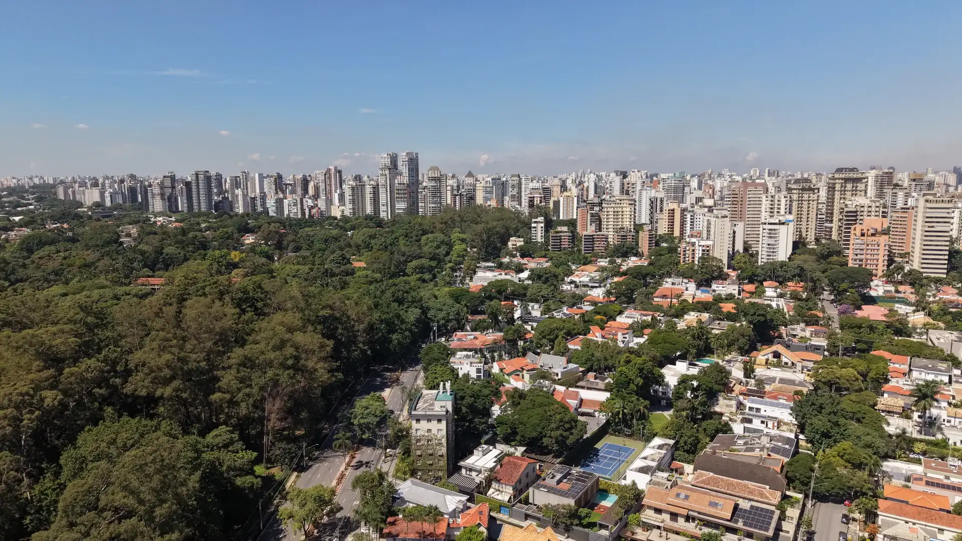 A mata do Parque Ibirapuera, casas e a linha de edifícios da cidade. Foto aérea.